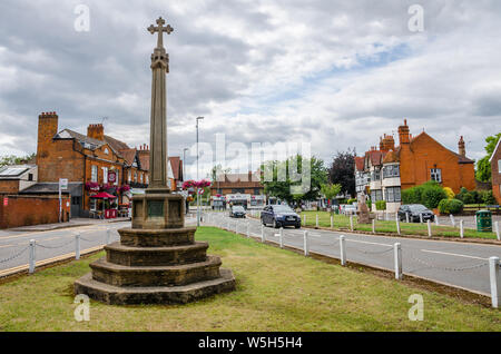 Ein Steinkreuz steht auf einem Grün in der Mitte der Berkshire Dorf Datchet in Großbritannien. Stockfoto