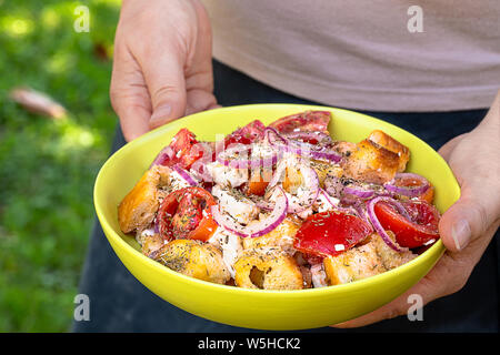 Frau mit Salat mit Feta, Tomaten, roten Zwiebeln und Brot Croutons getränkt in extra natives Olivenöl, gewürzt mit getrockneten Oregano. Stockfoto