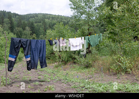 Seil mit nassen Kleidern in der Open Air im Lager. Touristische leben - Kleidung in der offenen Luft getrocknet. Im Regen getränkt Stockfoto