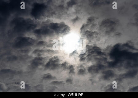 Dunkle Wolken, der Himmel schwarz, Sonne im Zentrum. Vor Regenwolken. Stockfoto