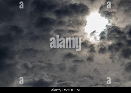 Dunkle Wolken, der Himmel schwarz, Sonne im Zentrum. Vor Regenwolken. Stockfoto