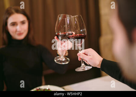 Schöne junge Paar mit Gläser Rotwein in Luxus Restaurant Stockfoto