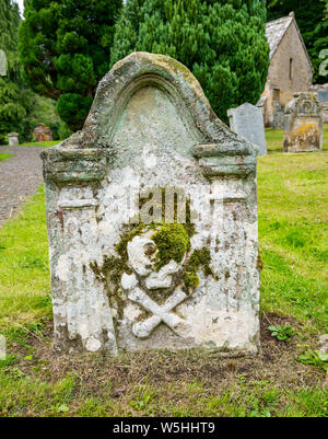 Alter abgenutzter Schädel und Kreuzknochen auf dem Grab auf dem Friedhof, Humbie Parish Church, East Lothian, Schottland, Großbritannien Stockfoto