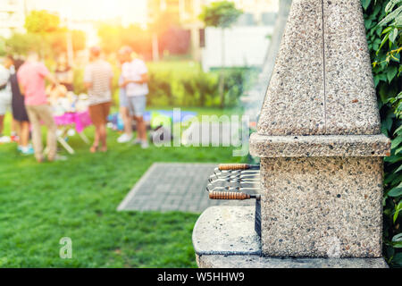 Outdoor Stein Herd mit Grill und Spieße. Gesellschaft der Freunde bei der Grillparty im Park oder im Garten mit grünem Rasen und brazier. Die Menschen, die Stockfoto