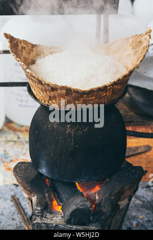 Weiß laotischen Dampf Reis kochen am Holzofen in Luang Prabang, Laos. Vertikale Ausrichtung Stockfoto