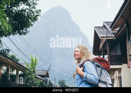 Junge kaukasier blonde Frau mit Rucksack auf der zentralen Straße von Muang Ngoi Dorf, Laos. Stockfoto