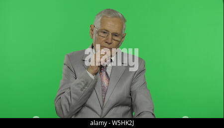 Älteren Geschäftsmann in Anzug denkt über etwas. Alte nachdenklich älterer Mann in formalen Verschleiß auf Chroma Key Hintergrund. Für ihr Logo oder Text platzieren. Grüner Hintergrund Stockfoto