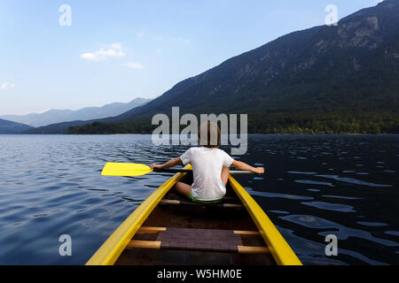 Kind in der Front eines Kanu paddeln auf der ruhigen See Bohinj, Slowenien, Europa Stockfoto