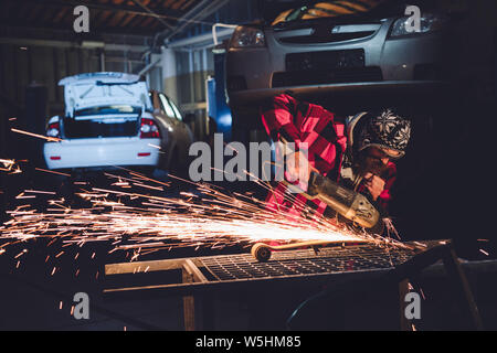 Die Mitarbeiter des Service Station produziert Körper Reparatur mit einem Schweißgerät in der Hand Funken Stockfoto