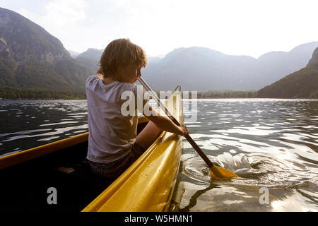 Kind in der Front eines Kanu paddeln auf der ruhigen See Bohinj, Slowenien, Europa Stockfoto