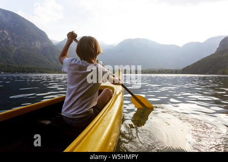 Kind in der Front eines Kanu paddeln auf der ruhigen See Bohinj, Slowenien, Europa Stockfoto