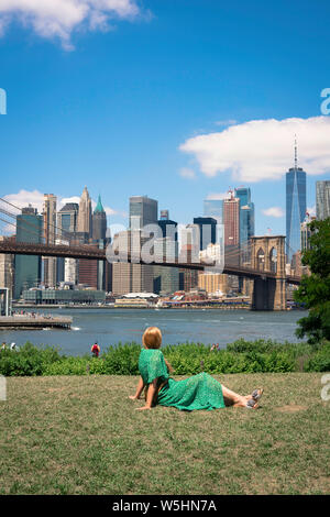 New York Skyline, Ansicht der Rückseite einer Frau, die sich in der Main Street Park, Brooklyn, am unteren Skyline von Manhattan, New York City suchen. Stockfoto