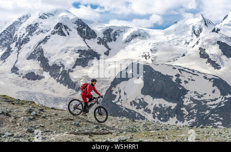 Active Senior, Frau, reiten Ihr elektrische Mountainbike auf dem Gornergrat bei Zermatt, Wallis, Schweiz. Im Hintergrund Gornergletscher, Monte Rosa Stockfoto