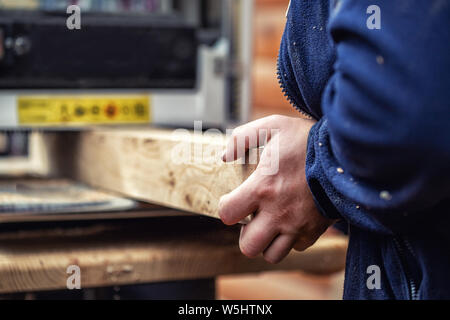Handwerker Holzbearbeitung in der Zimmerei mit vielen modernen professionellen Elektrowerkzeugen. Mann mit Dickeckenmaschine und Kreissäge und andere Geräte Stockfoto