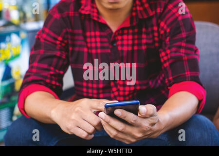 Männer tragen rot gestreiften Shirts mit Handys in Cafés Stockfoto