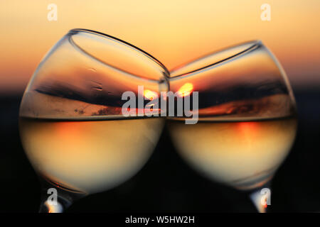 Weingläser auf Sonnenuntergang Hintergrund, die Abendsonne in einem Beschlagenen Glas reflektiert wird. Konzept der Feier, Paare auf einer Liebe, romantische Cocktail Stockfoto