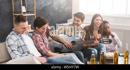 Home Party. Freunde, Gitarre zu spielen, Karaoke singen und Spaß haben Stockfoto