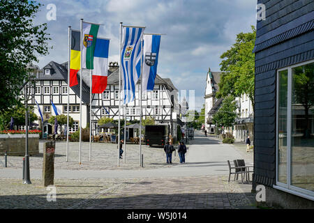 Der Marktplatz in Brilon ist mit Fahnen geschmückt. Ansicht von Friedrich Straße. Fachwerkhäuser am Marktplatz, Brunnen und Evangelische Kirche Stockfoto