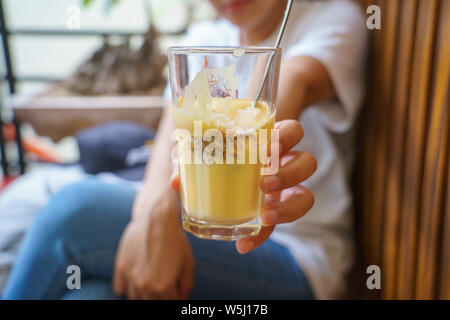 Frau mit einem vietnamesischen ei Kaffee heiß und kühl in den weißen Kaffeebecher, Tasse in Hanoi, Vietnam Stockfoto