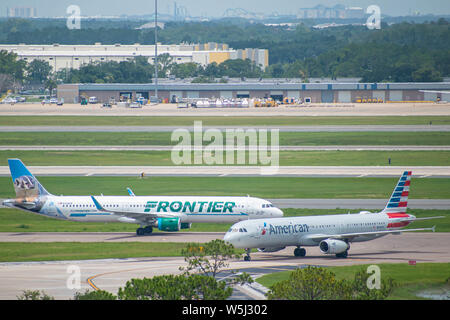Orlando, Florida. Juli 09, 2019. Frontier und American Airlines Flugzeuge auf der Piste vorbereiten für den Abflug vom Internationalen Flughafen Orlando MCO Stockfoto