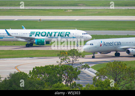 Orlando, Florida. Juli 09, 2019. Frontier und American Airlines Flugzeuge auf der Piste vorbereiten für den Abflug vom Internationalen Flughafen Orlando MCO Stockfoto
