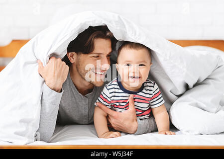 Verspielt Vater versteckt unter Decke mit Baby Sohn Stockfoto