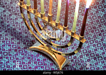 Ein Davidstern themed hanukkiah oder Chanukka Kerzenhalter sitzt auf einem gemusterten Tuch. Stockfoto