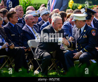 Von links: Gerard Fitzgerald, uniformierten Feuerwehrmann-verbindung Präsident, und Jake Lemonda, Präsident der Uniformierten Fire Officers Association, sehen Sie auf wie Philip Alvarez schüttelt Hände mit ehemaligen Fire Chief der Manhattan firehouse Chief John Joyce vor dem Präsidenten der Vereinigten Staaten Donald J. Trumpf Unterzeichnung H.R. 1327, eine Tat, die dauerhaft im September 11 Fonds zur Entschädigung der Opfer, im Rosengarten des Weißen Hauses in Washington, DC am Montag, 29. Juli 2019 genehmigen. Credit: Ron Sachs/Pool über CNP/MediaPunch Stockfoto