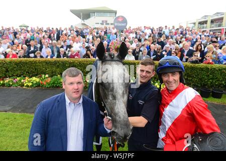 Jockey Davy Russell mit Trainer Gordon Elliott und Bräutigam Jack Madden nach dem Gewinn der Galway Bay Hotel & Galmont Anfänger Hürde onboard Tödliche Schritte während der Tag einer der 2019 Summer Festival im Galway Pferderennbahn. Stockfoto