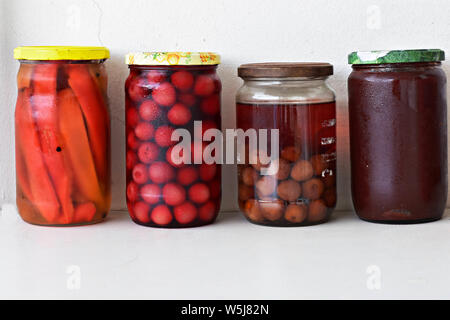 Vielzahl von haltbar gemachten Lebensmitteln in Gläsern - Konfitüre, Marmelade, Kirschen, rote Paprika, Gemüse und Früchte. Fermentierter Lebensmittel. Herbst canning. Stockfoto