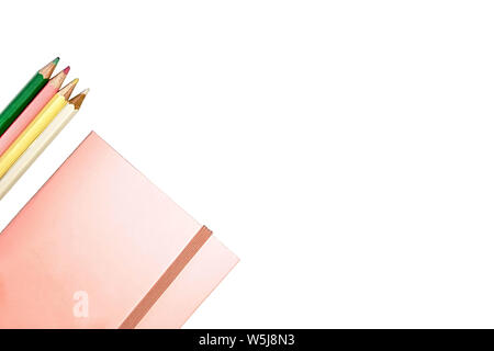 Piink Notizbuch aus Papier und vier Farbstifte, isoliert Stockfoto