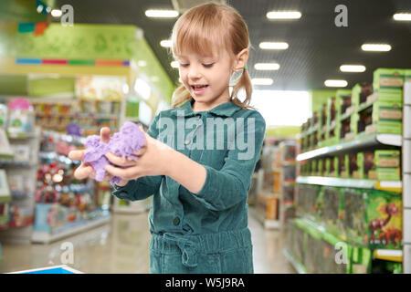 Moderne Spielwaren für Entwicklung in den Lagern der Kinder Spielzeug. Gerne hübsche Mädchen spielen mit violett kinetische Sand in Shopping Center. Kind im Zimmer spielen von speichern. Stockfoto