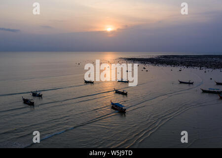 Antenne drone Ansicht der traditionellen Longtail Boote vor Anker während eines tropischen Sonnenuntergang über dem Meer. Stockfoto