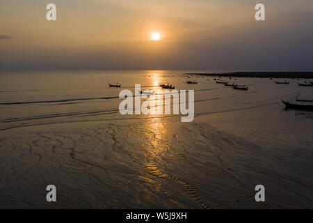 Antenne drone Ansicht der traditionellen Longtail Boote vor Anker während eines tropischen Sonnenuntergang über dem Meer. Stockfoto