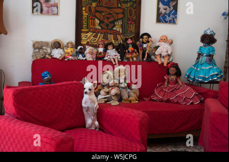 Chihuahua Hund sitzt oben auf seinen Hinterbeinen auf einem Sofa von Spielzeug in einem Haus in Havanna, Kuba umgeben Stockfoto