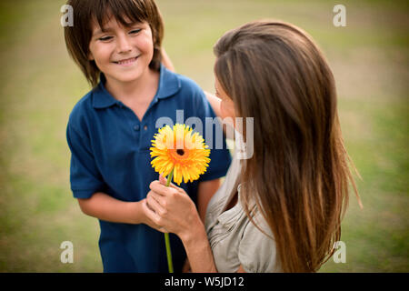 Junge seine Mutter eine Sonnenblume. Stockfoto