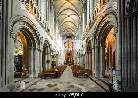 Ein Historiker sitzt auf einem Gerüst in einer kleinen Kapelle in der Kathedrale von Bayeux Bayeux Frankreich als Touristen besuchen die gewölbte Kirchenschiff. Stockfoto