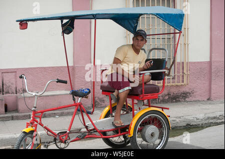 Jungen kubanischen Fahrrad taxi Chauffeur entspannt auf seinem Fahrrad Stockfoto