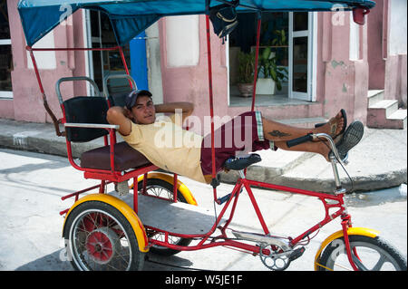 Jungen kubanischen Fahrrad taxi Chauffeur entspannt auf seinem Fahrrad Stockfoto