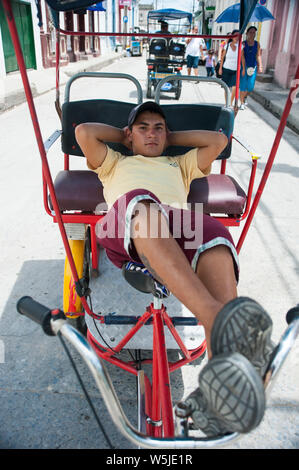 Jungen kubanischen Fahrrad taxi Chauffeur entspannt auf seinem Fahrrad Stockfoto