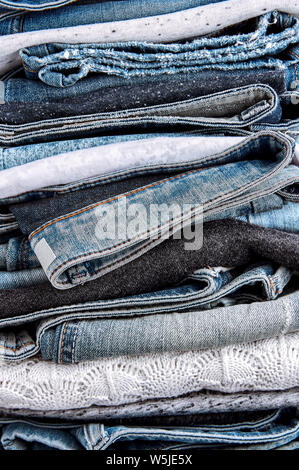 Nahaufnahme der Stapel der blauen Jeans, Pullover und Shirts Stockfoto