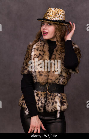 Mädchen Modell in Pelzmantel und Leopard hat auf grauem Hintergrund posiert im Studio Stockfoto