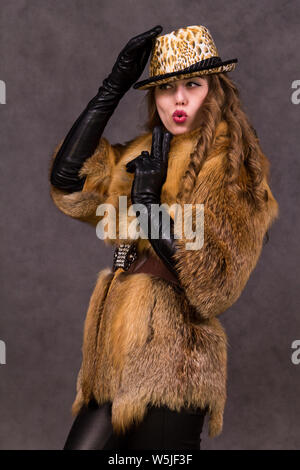 Mädchen Modell in Pelzmantel und Leopard hat auf grauem Hintergrund posiert im Studio Stockfoto