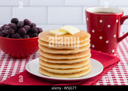 Stapel von frisch zubereiteten Pfannkuchen auf einem karierten Tischtuch Stockfoto