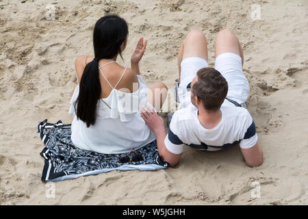 Ein junges Paar entspannende an einem Sommertag am Strand an der Londoner South Bank, in der Nähe der Themse. Stockfoto