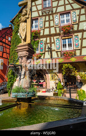 Bunte Fachwerkhaus mit Gemälden in der Stadt Kaysersberg, Elsass, Frankreich, alten Brunnen vor Stockfoto