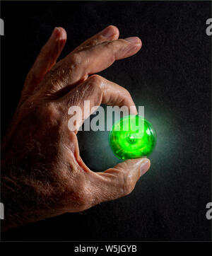 Glühende Glaskugel in der Hand des Menschen vor hellem Licht statt. Stockfoto