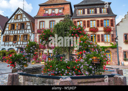 Dorf Bergheim, Elsass, Frankreich, alte Brunnen vor der Hälfte geschmückten Fachwerkhäusern Stockfoto