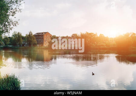 Alte Gebäude auf dem See in den Strahlen der untergehenden Sonne. Landschaft von Minsk, Weißrussland. Stockfoto