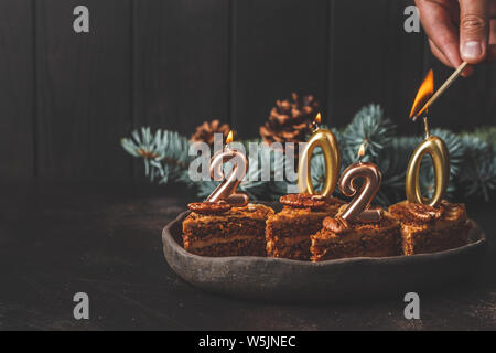 Das neue Jahr 2020. Festliche Kuchen mit Kerzen auf einem dunklen Hintergrund, kopieren. Stockfoto